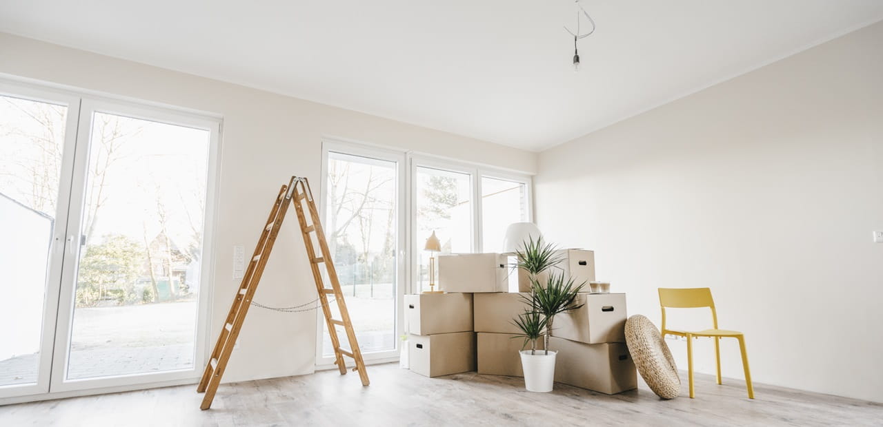 Moving boxes and ladder in empty room of a new home