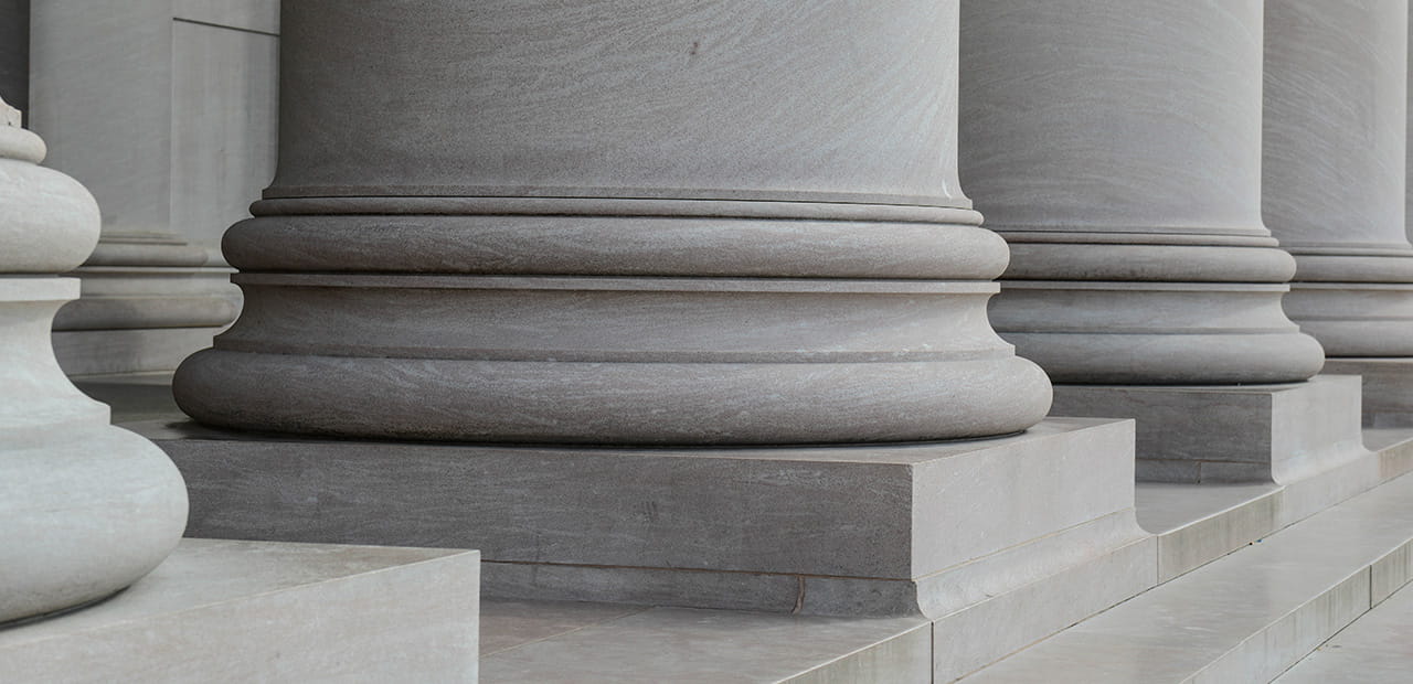 ) Close-up of government building columns, symbolizing the U.S. political landscape and the potential impact of midterm election outcomes on financial markets and economic policy.