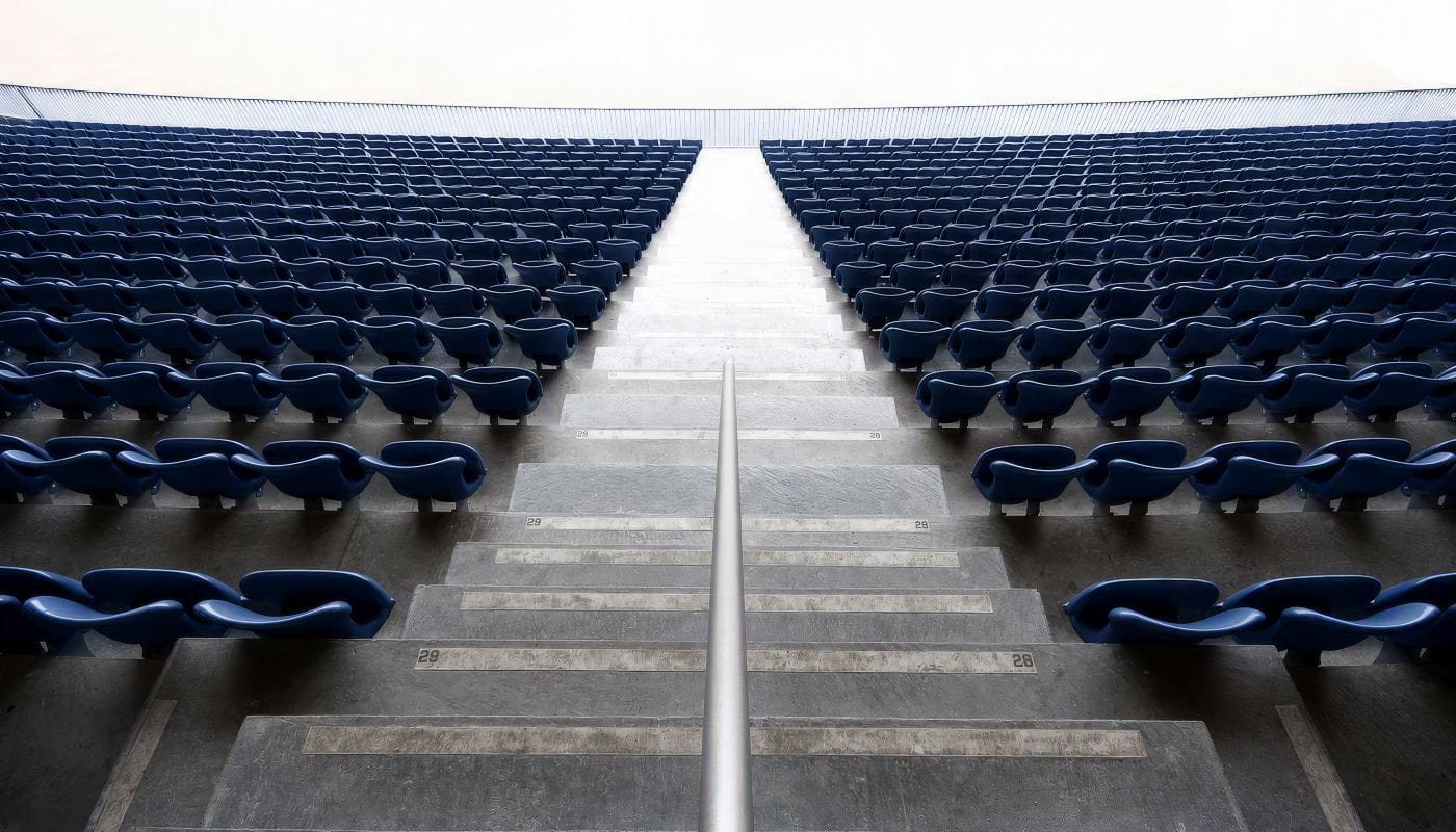 Empty stadium seating symbolizes the inverted wealth lifecycle of professional athletes, who often earn peak income early in life and must sustain it long after their playing careers end.